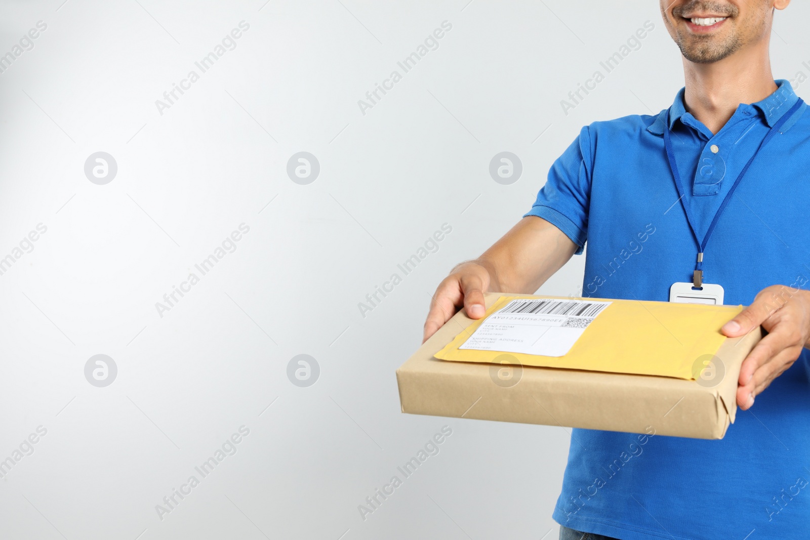 Photo of Happy young courier with parcel and envelope on white background, closeup