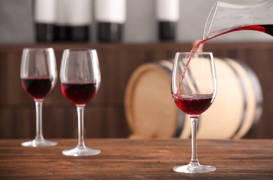 Photo of Pouring delicious red wine into glass on table