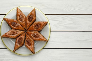 Photo of Delicious sweet baklava with walnuts on white wooden table, top view. Space for text