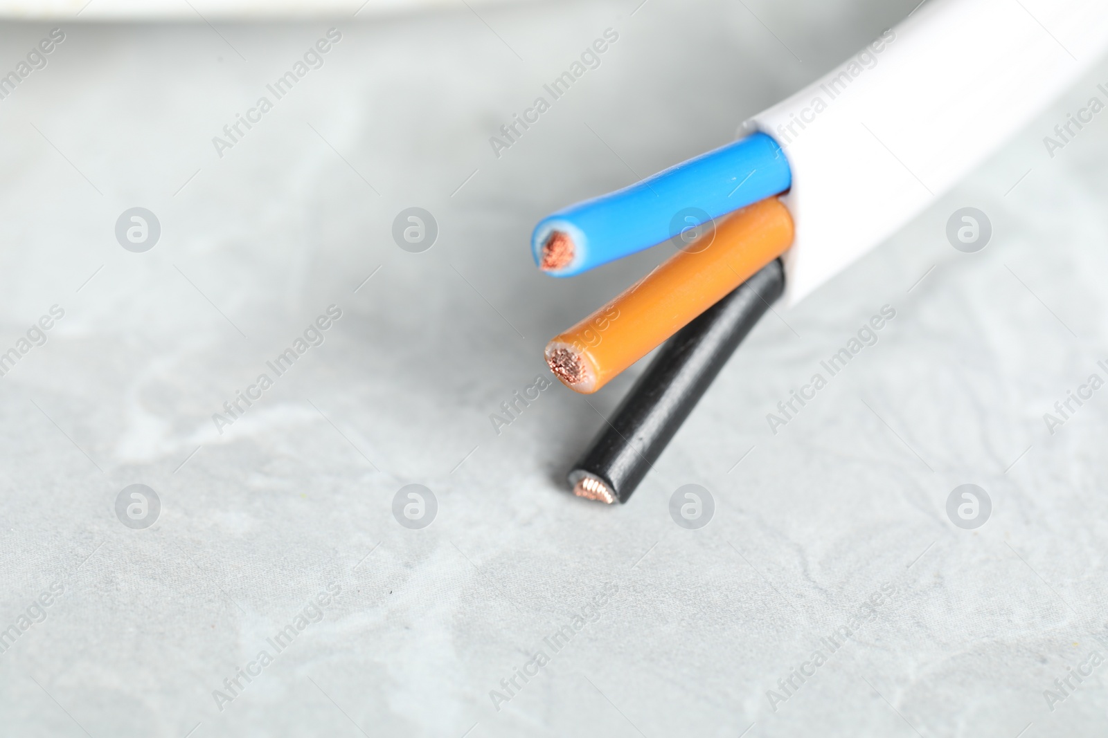 Photo of Colorful electrical wire on gray textured surface, closeup. Space for text