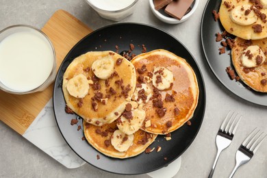 Tasty pancakes with sliced banana served on light grey table, flat lay