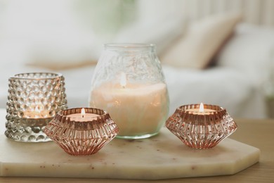 Set of scented candles on wooden table in bedroom, closeup