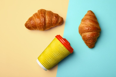 Paper coffee cup and croissants on color background, flat lay