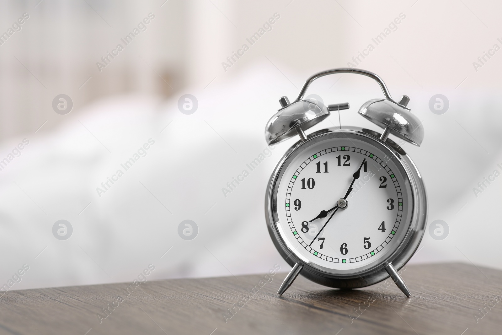 Photo of Silver alarm clock on wooden table indoors. Space for text