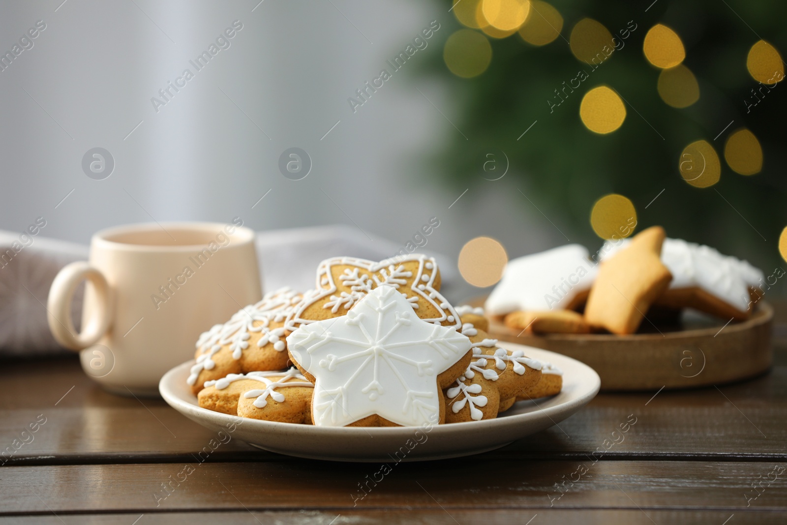 Photo of Decorated cookies and hot drink on wooden against blurred Christmas lights