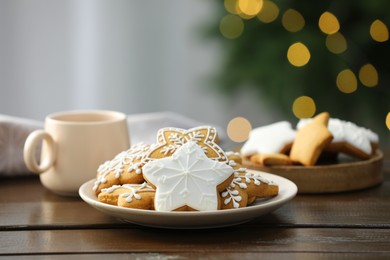 Decorated cookies and hot drink on wooden against blurred Christmas lights