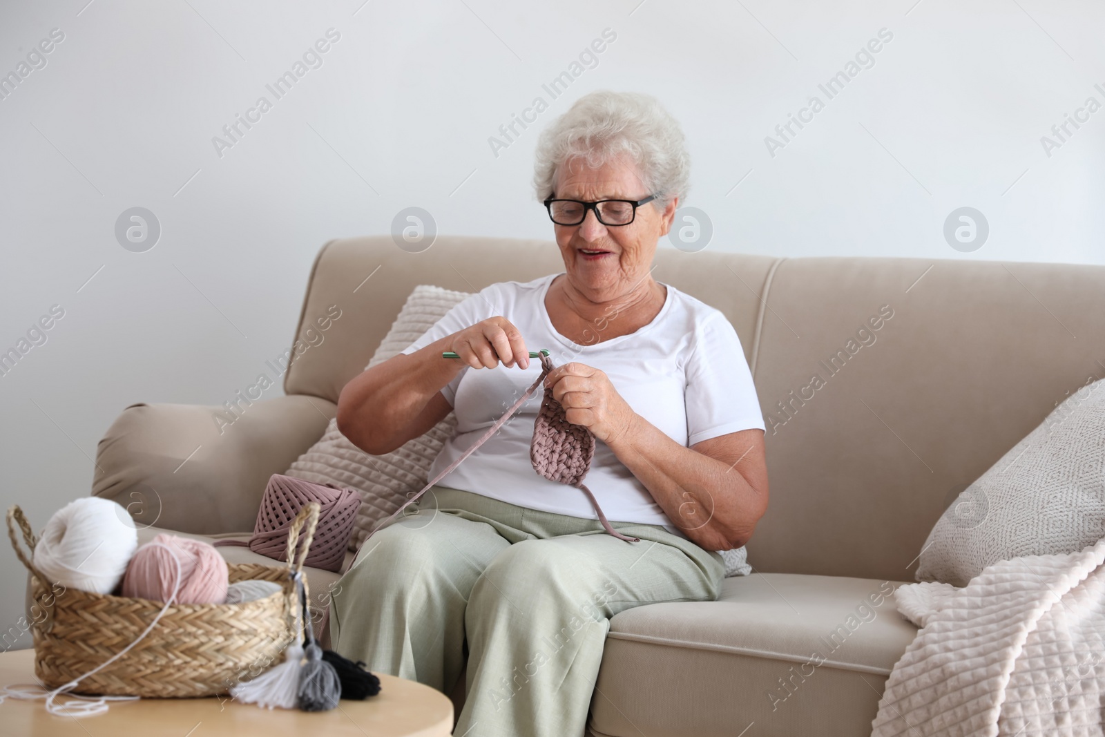 Photo of Elderly woman crocheting at home. Creative hobby