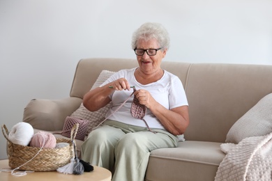 Elderly woman crocheting at home. Creative hobby