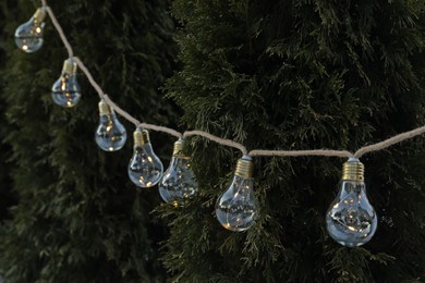 Photo of Beautiful garland of lamp bulbs hanging outdoors. String lights