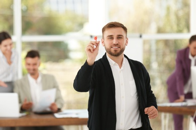 Happy young businessman with dart in office