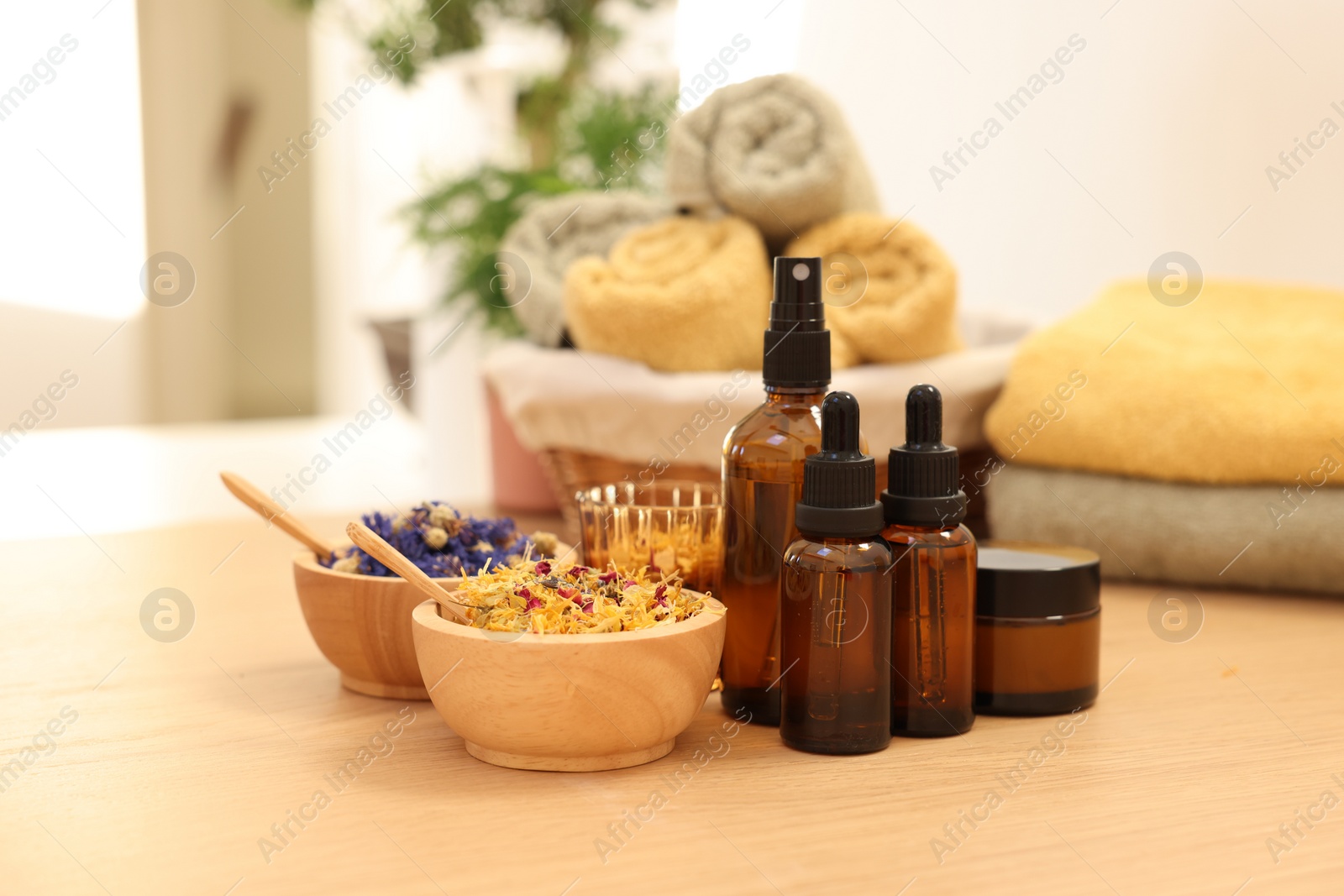 Photo of Dry flowers, bottles of essential oils and jar with cream on wooden table indoors. Spa time