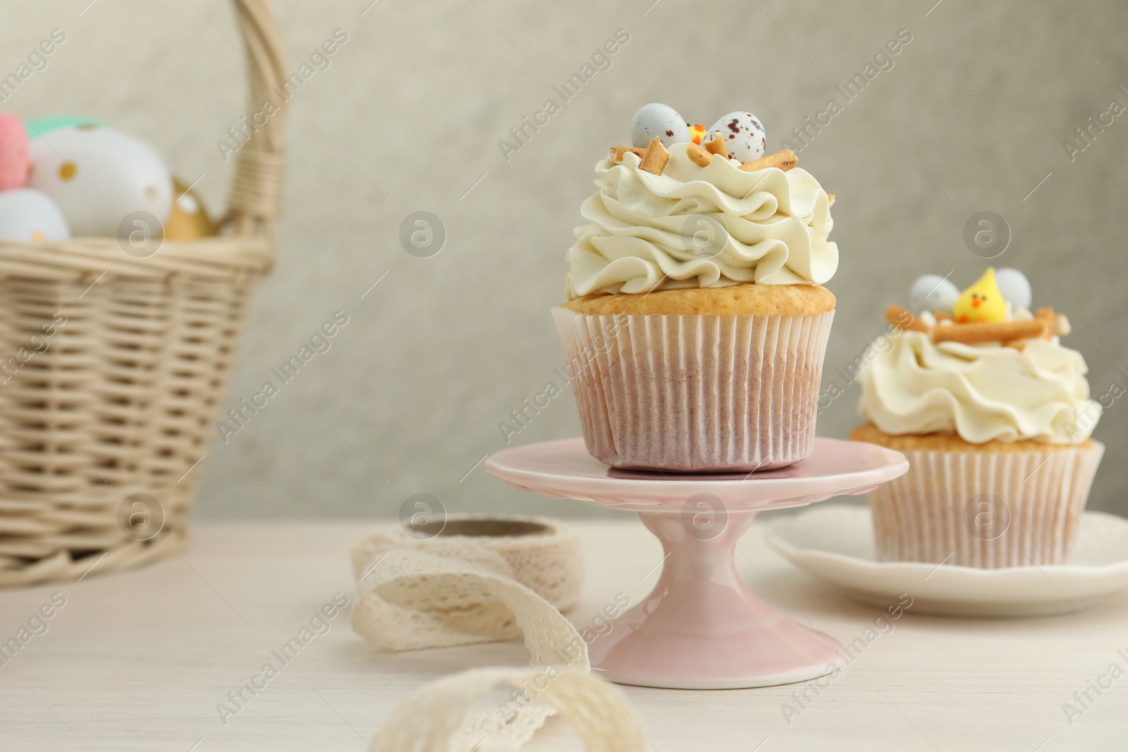 Photo of Tasty Easter cupcakes with vanilla cream on light wooden table