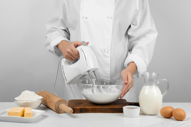 Woman whipping egg whites at wooden table, closeup. Baking pie