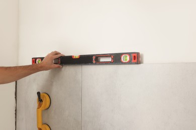 Photo of Worker installing tiles indoors, closeup. Home improvement
