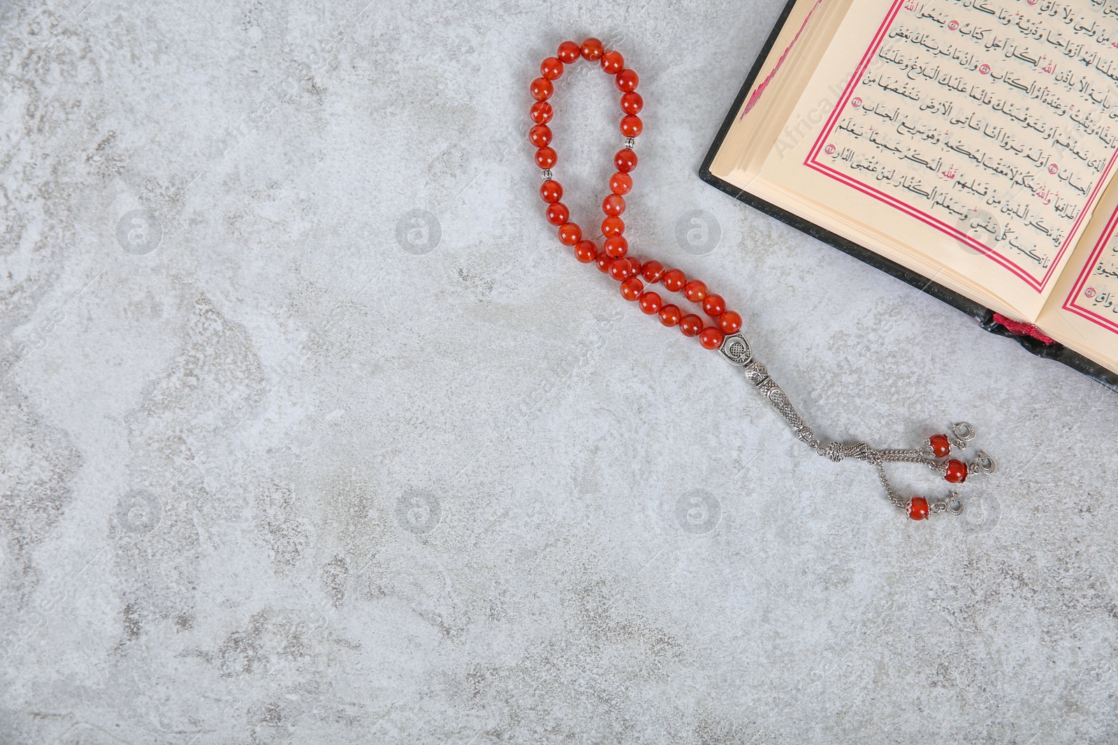 Photo of Muslim prayer beads, Quran and space for text on grey background, top view