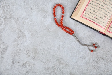 Photo of Muslim prayer beads, Quran and space for text on grey background, top view