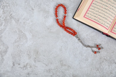 Muslim prayer beads, Quran and space for text on grey background, top view