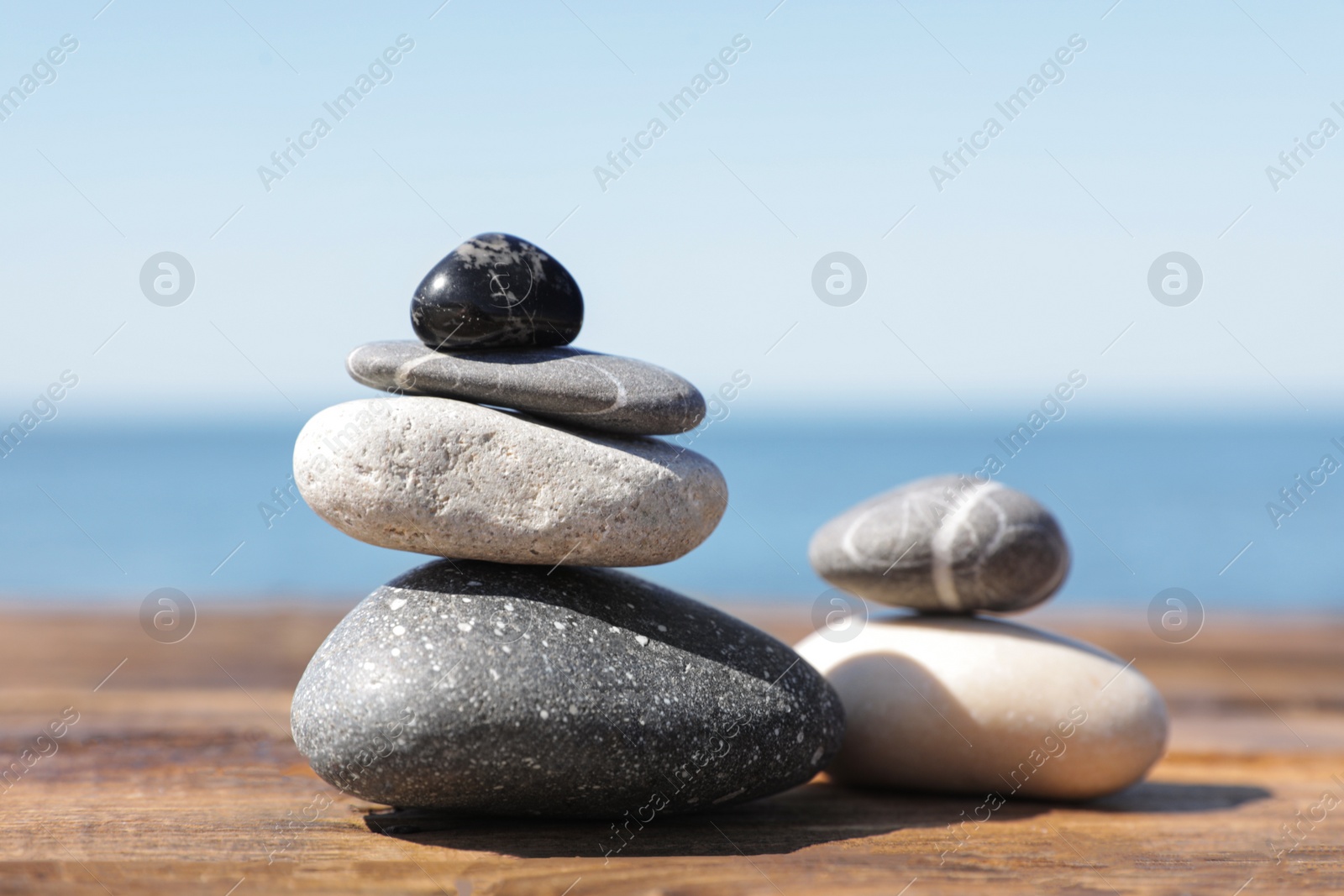 Photo of Stacks of stones on wooden pier near sea. Zen concept