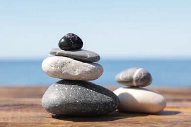 Photo of Stacks of stones on wooden pier near sea. Zen concept