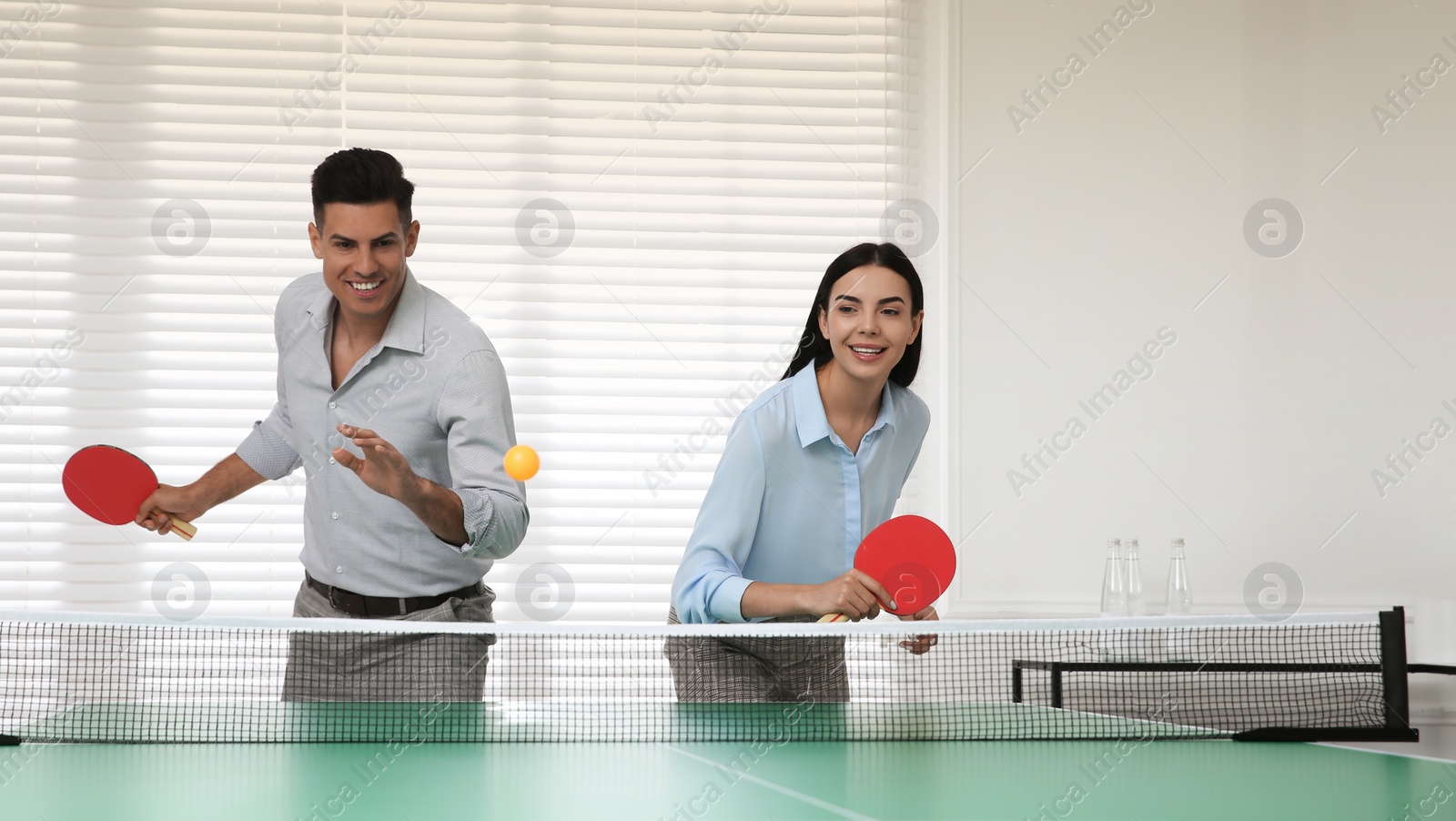 Photo of Business people playing ping pong in office