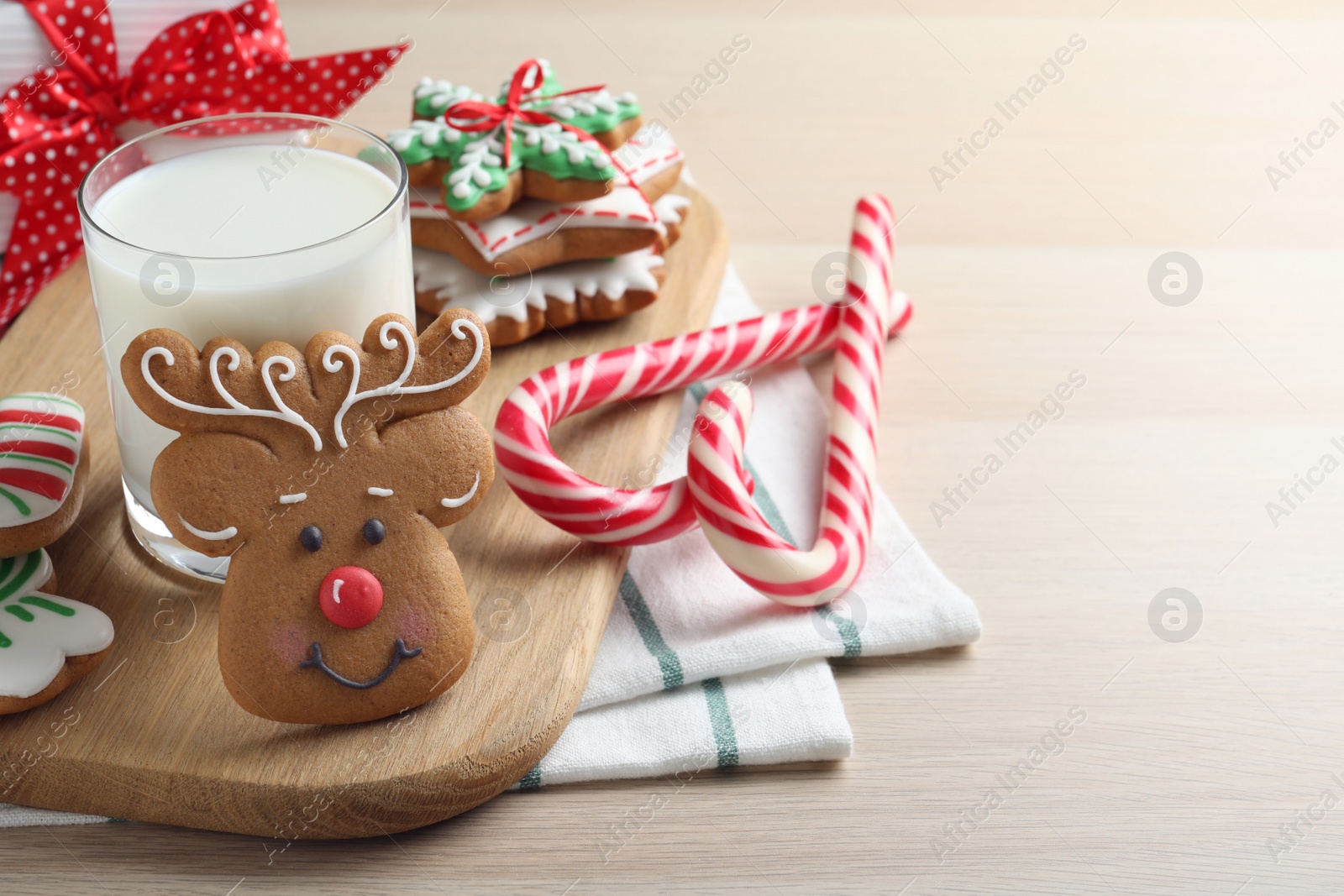 Photo of Decorated Christmas cookies and glass of milk on wooden table. Space for text