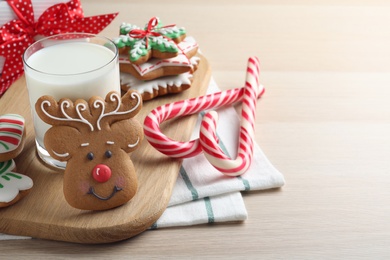 Photo of Decorated Christmas cookies and glass of milk on wooden table. Space for text