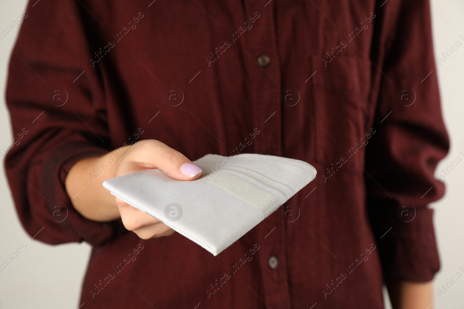 Photo of Woman holding handkerchief against light background, closeup