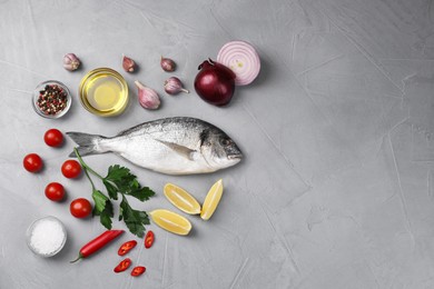 Photo of Flat lay composition with raw dorado fish and vegetables on grey table. Space for text