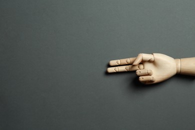 Wooden mannequin hand on grey background, top view. Space for text