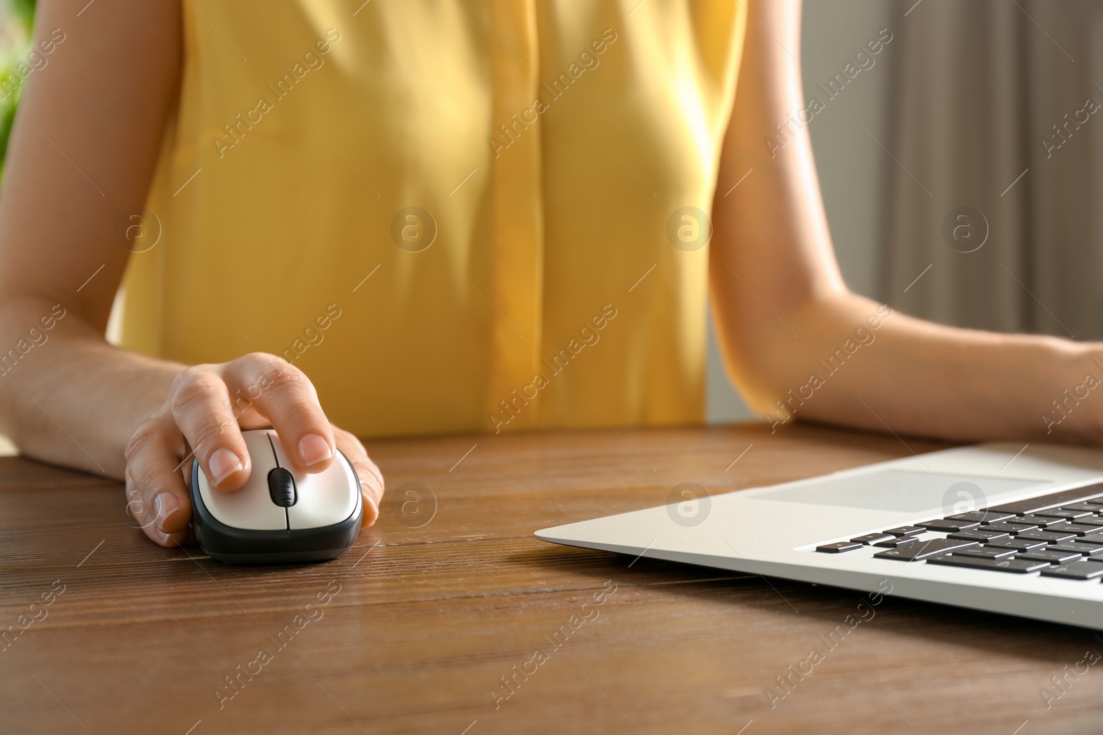 Photo of Woman using computer mouse with laptop at table, closeup