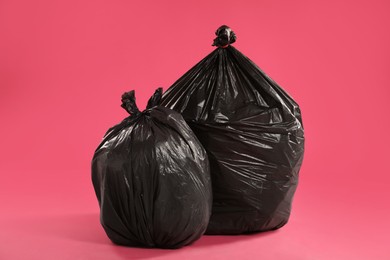 Trash bags full of garbage on pink background