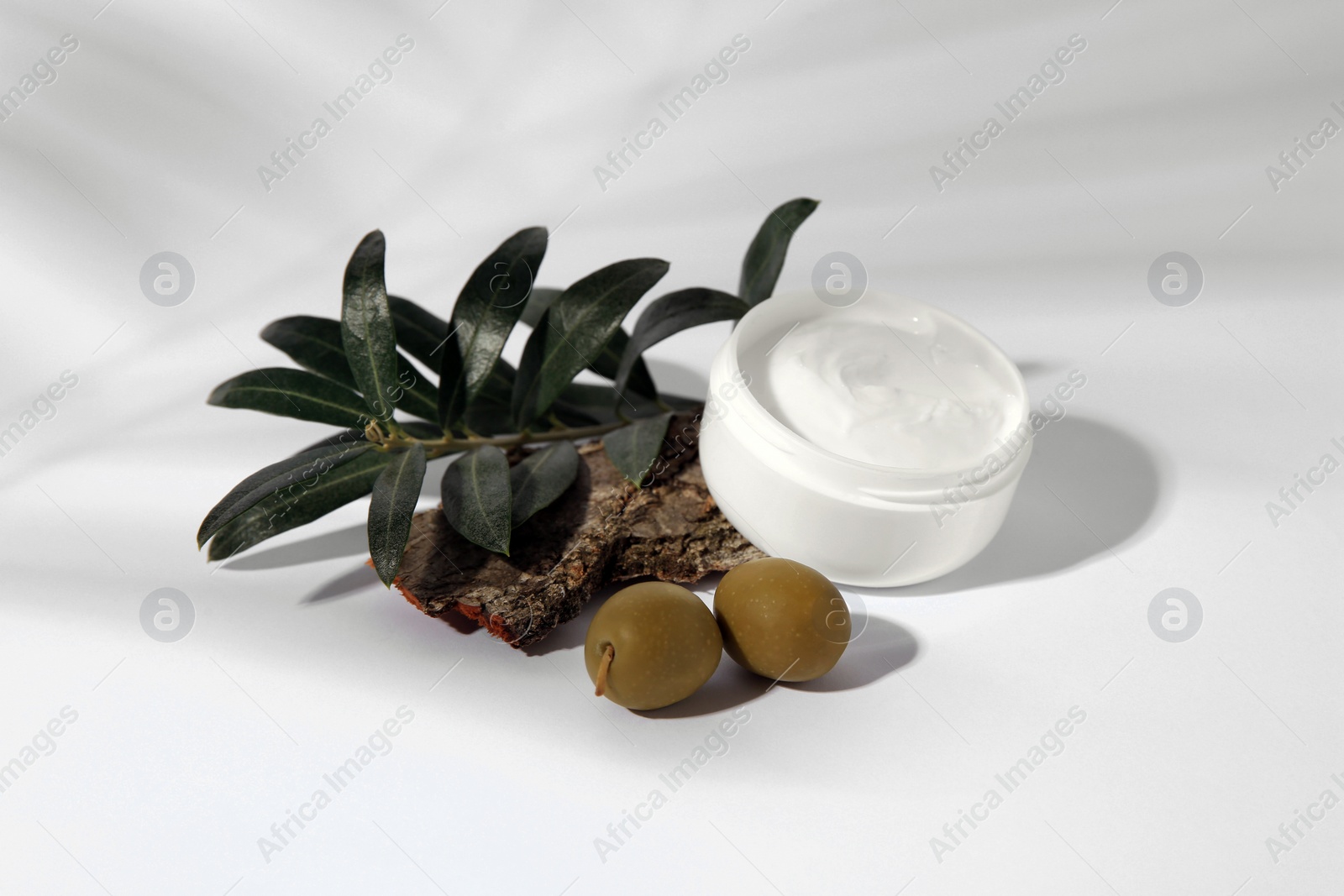 Photo of Jar of natural cream, stones and olives on white background. Cosmetic products