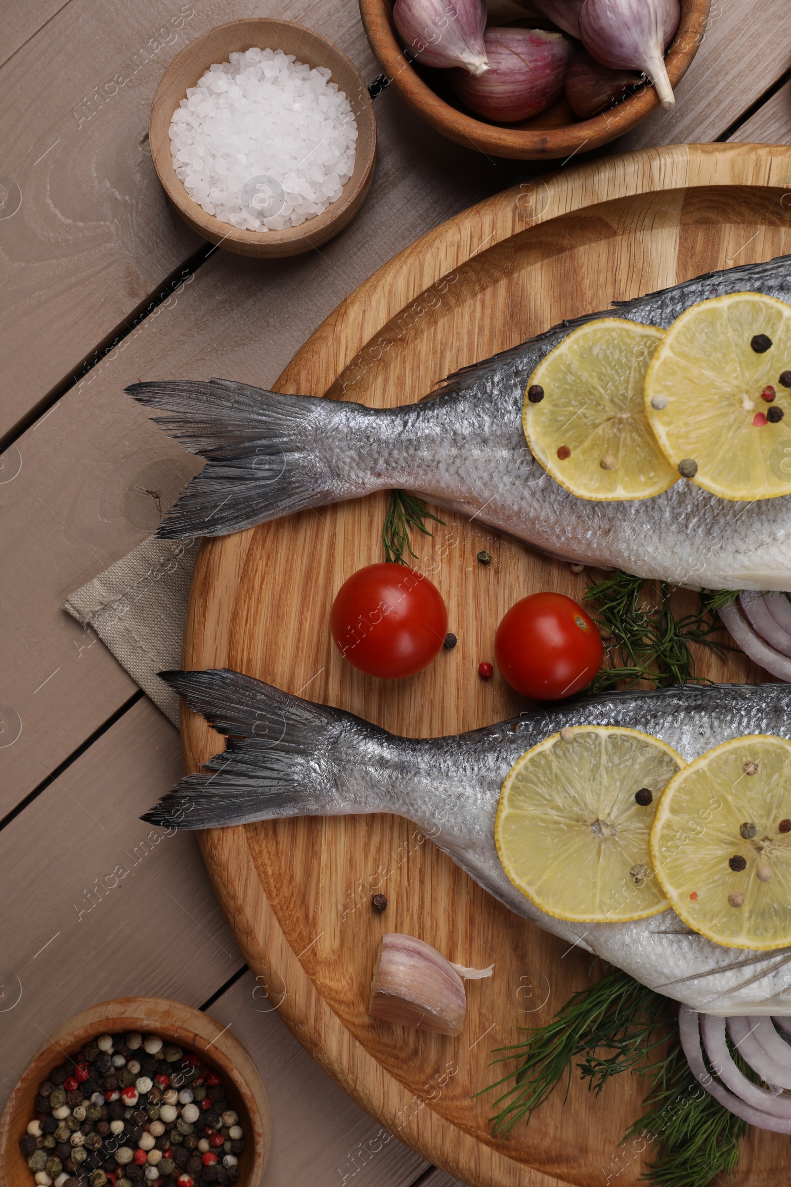 Photo of Raw dorado fish, lemon, spices and tomatoes on wooden table, flat lay