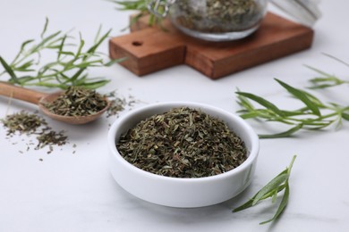 Dry and fresh tarragon on white table