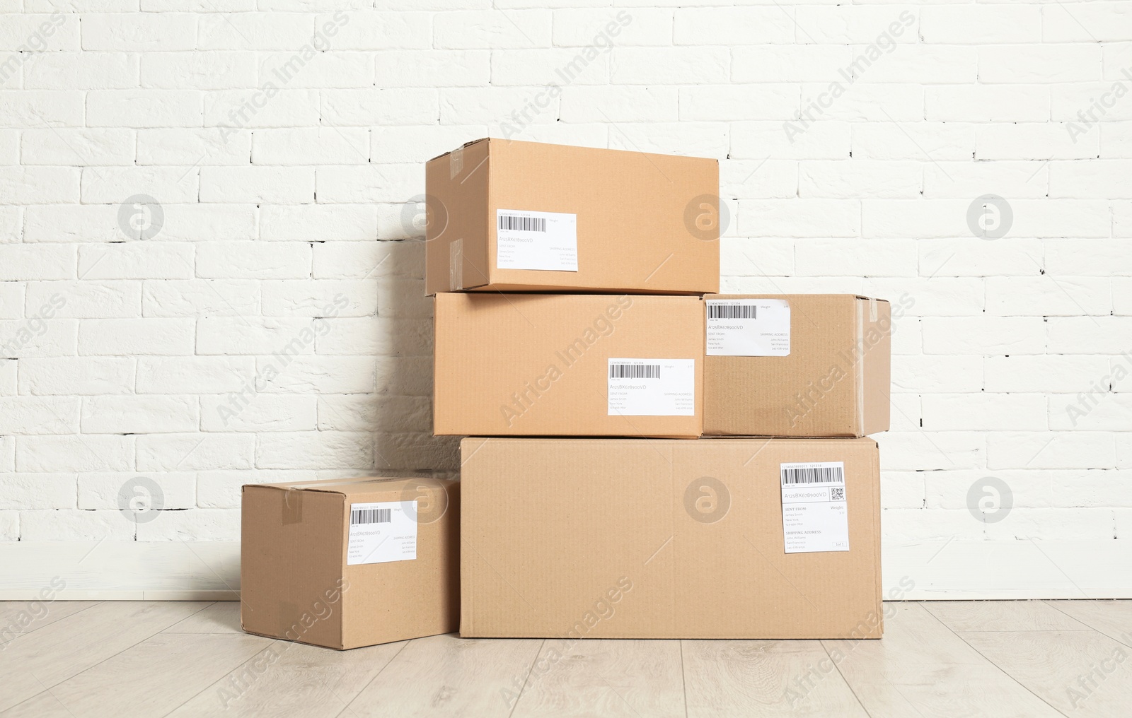 Photo of Stack of parcel boxes on floor against brick wall