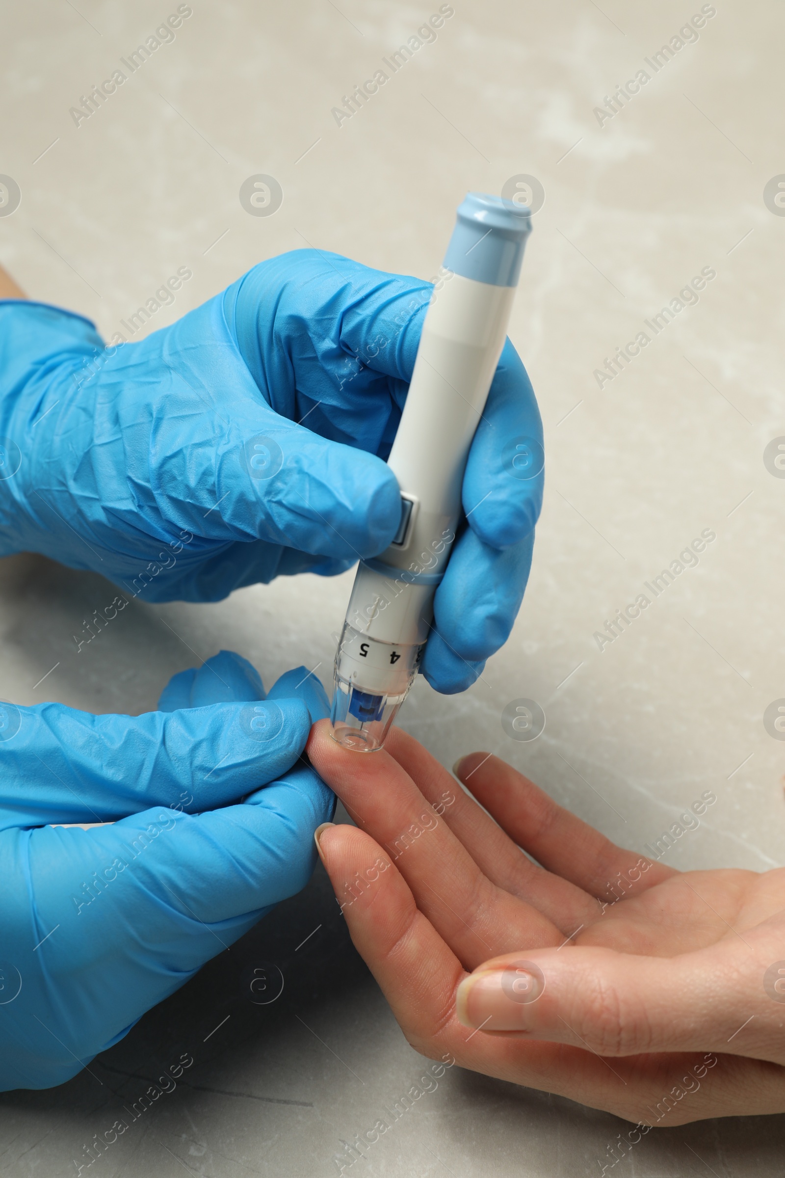 Photo of Diabetes. glucose testing. Doctor using lancet pen at light table, closeup