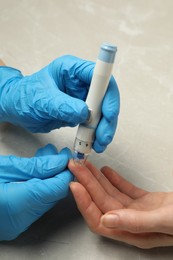 Diabetes. glucose testing. Doctor using lancet pen at light table, closeup