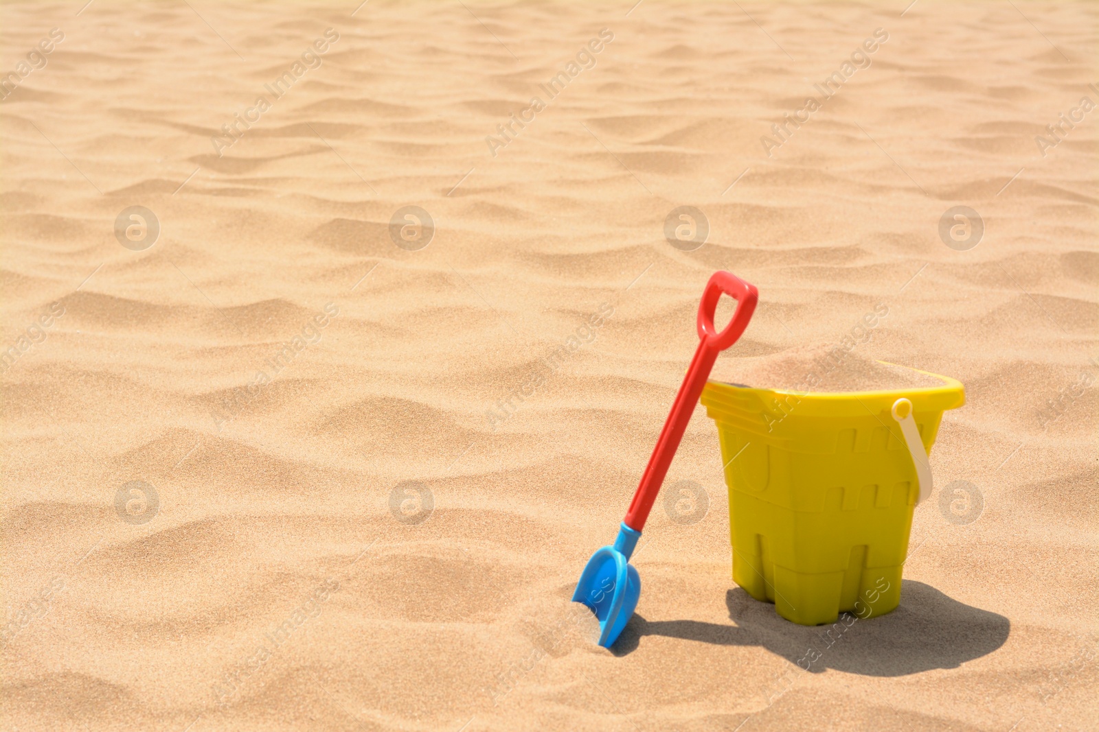 Photo of Plastic bucket and shovel on sand, space for text. Beach toys