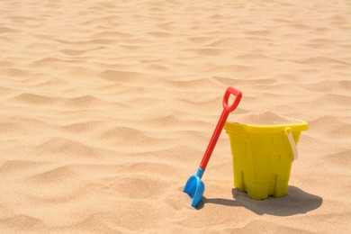 Plastic bucket and shovel on sand, space for text. Beach toys