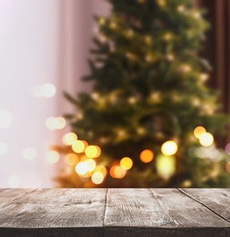 Image of Empty wooden surface and blurred view of Christmas tree in room, space for text. Interior design