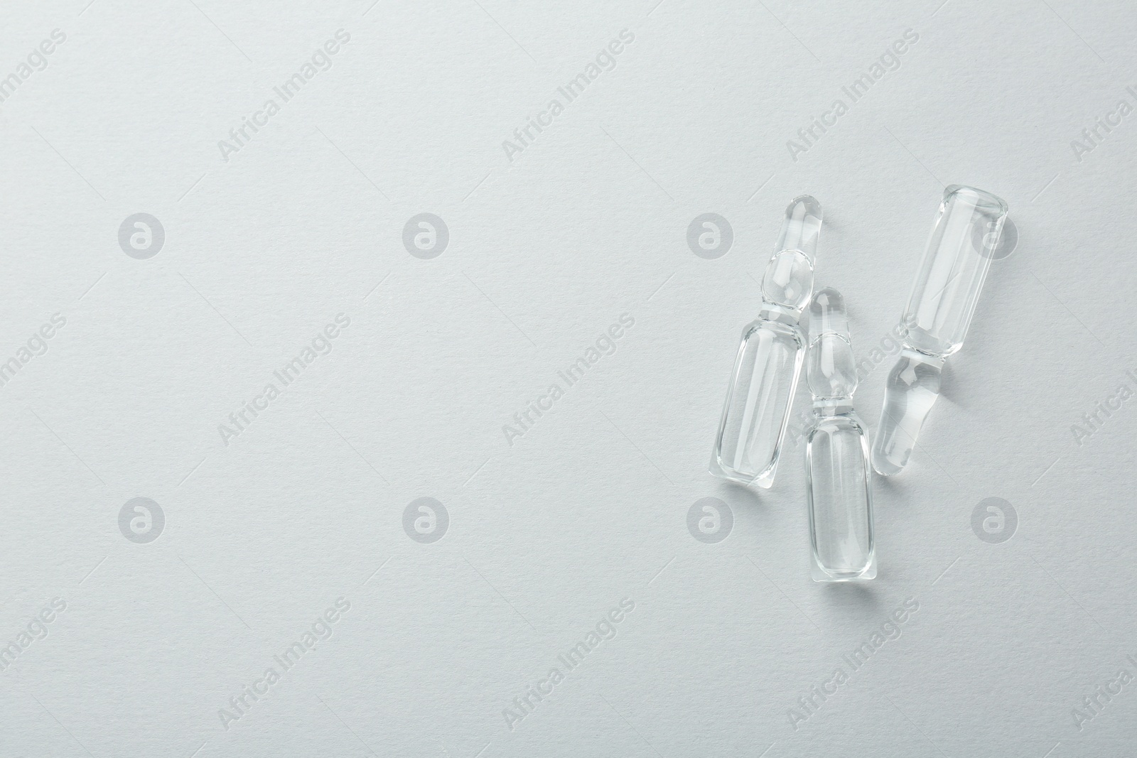 Photo of Glass ampoules with liquid on white background, top view. Space for text