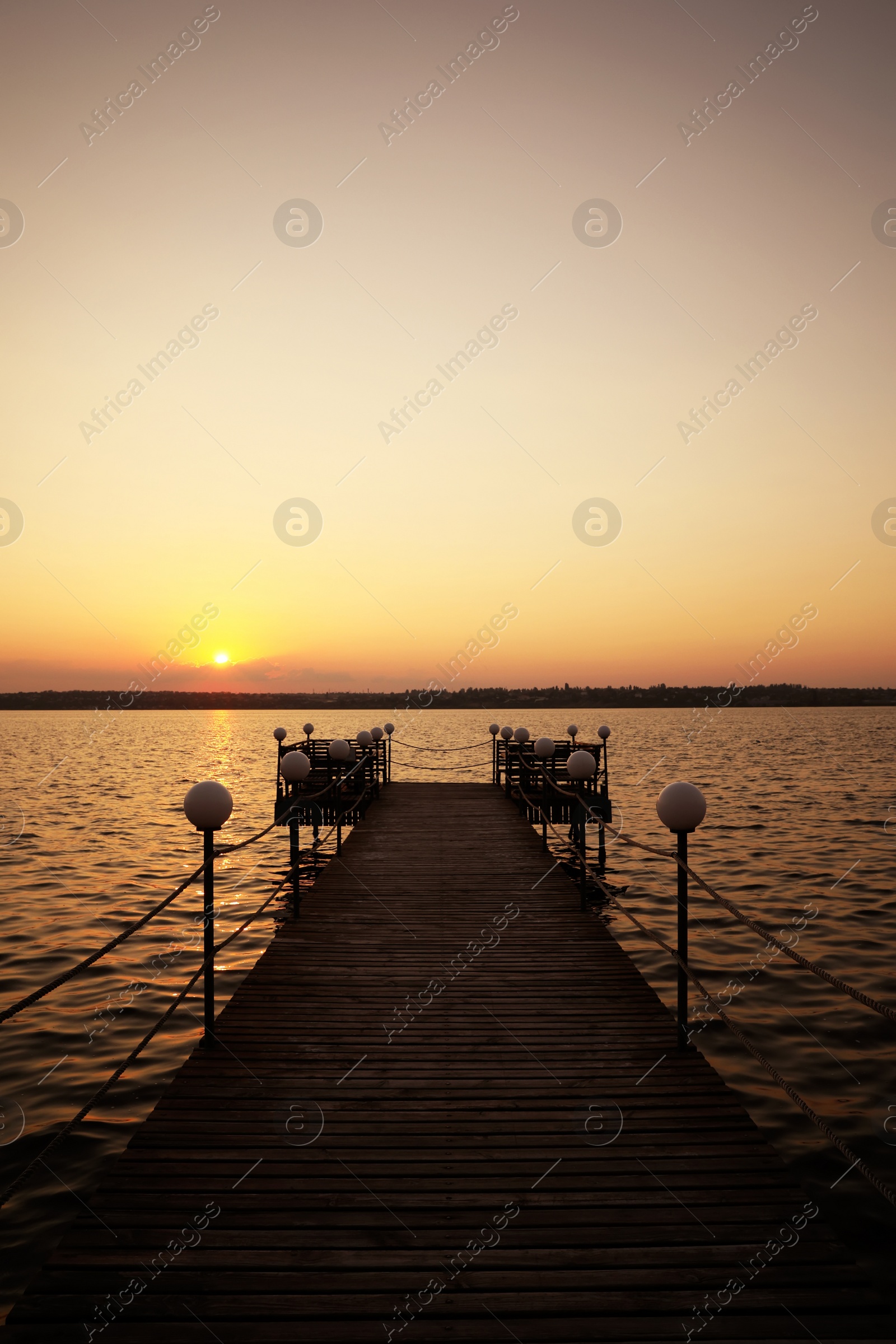 Photo of Picturesque view of empty wooden pier with lanterns at sunset