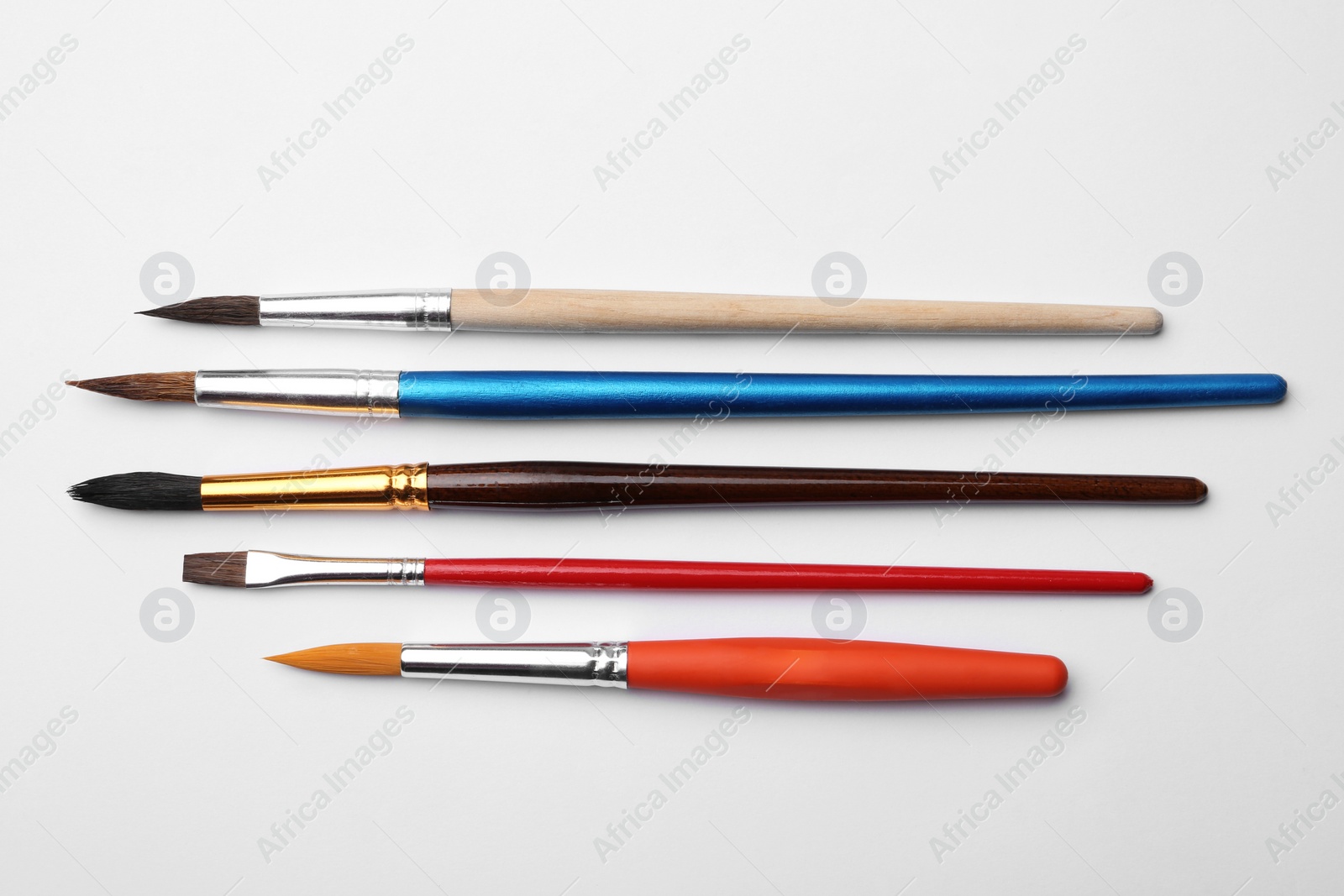 Photo of Different paint brushes on white background, top view