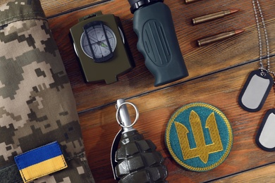Photo of MYKOLAIV, UKRAINE - SEPTEMBER 26, 2020: Tactical gear, military uniform and Ukrainian army patches on wooden table, flat lay
