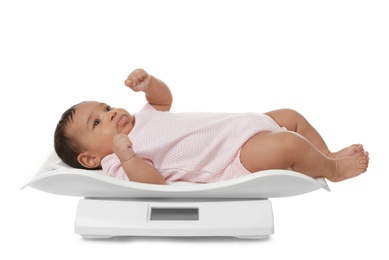 African-American baby lying on scales against white background