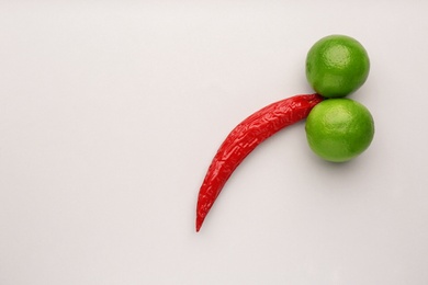 Photo of Chili pepper and limes symbolizing male sexual organ on white background, flat lay with space for text. Potency problem