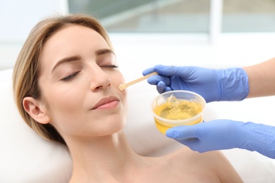 Photo of Beautiful woman getting wax epilation of face in salon