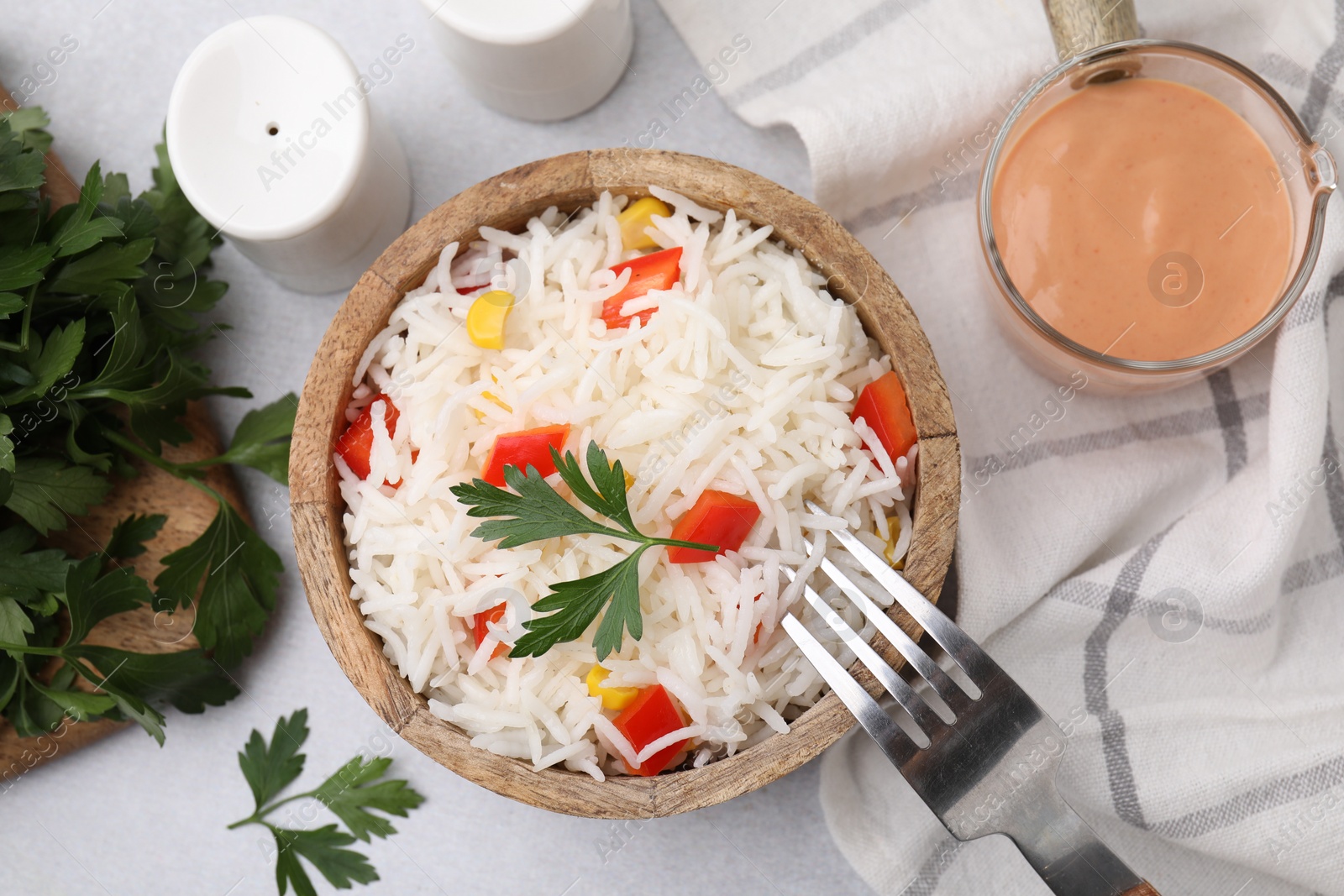 Photo of Bowl of delicious rice with vegetables and parsley served on table, flat lay