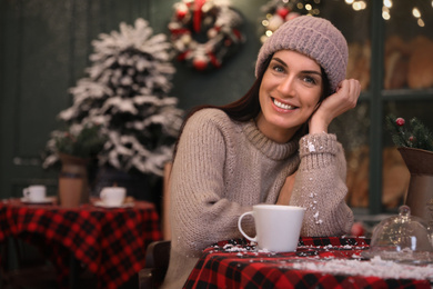 Photo of Beautiful woman at table in decorated cafe. Christmas celebration