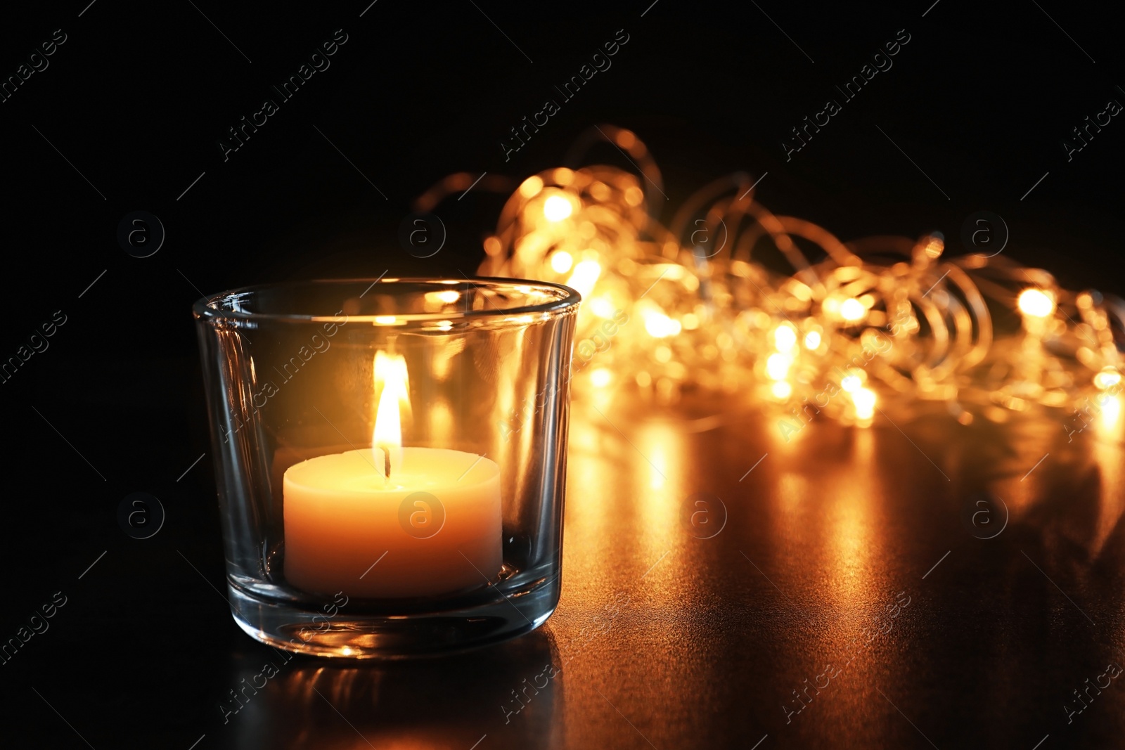 Photo of Wax candle burning on table in darkness, closeup